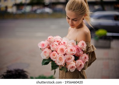 wonderful flower bouquet of beautiful pink roses in the hands of young handsome blonde woman