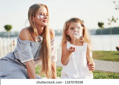 A wonderful girl child makes bubbles with her mom in the park. - Powered by Shutterstock