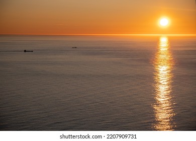 Wonderful landscapes in Norway. Nord-Norge. Beautiful scenery of a midnight sun sunset at Nordkapp (Cape North). Boat and globe on a cliff. Rippled sea and clear orange sky. Selective focus