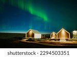 Wonderful Northern lights or Aurora borealis glowing over illuminated huts in autumn on arctic circle at Iceland