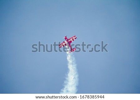 Similar – Red plane with propeller flying upward with white smoke