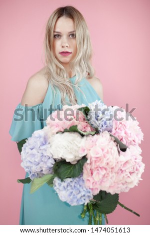 Happy blonde woman posing near a huge flower