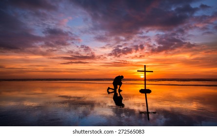 Wonderful reflection on a beach at sunset, with a man kneeling by it.
