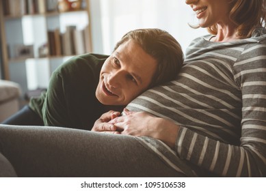 Wonderful sounds. Portrait of glad future father is hearing abdomen of pregnant woman with excitement. He is leaning head on tummy and laughing  स्टॉक फोटो