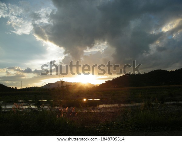 Wonderful sunset view\
from the car window. The sun sets over high mountains,Sun set\
through the tree