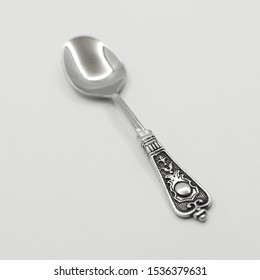 A wonderful teaspoon with a vegetable pattern lay on a white surface.
