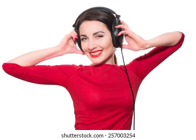 Wonderful teenager girl  listening to the music in big headphones in red clothes islolated on white background