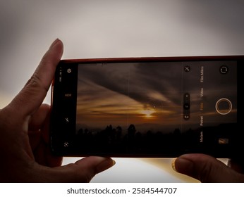 Wonosobo, Central Java, Indonesia, Tuesday, February 11, 2025. Silhouette taking sunset photos with handphone or gadgets