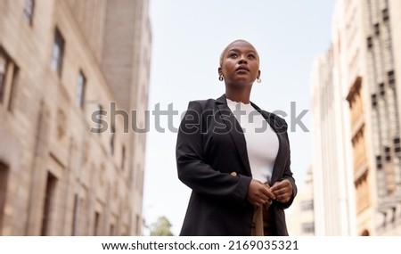 I wont stop till I realise my dream. Low angle shot of a young businesswoman looking thoughtful while standing in the city.
