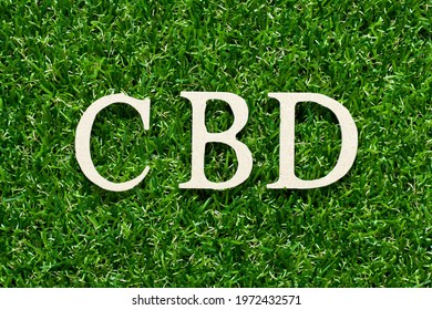 Wood alphabet letter in word CBD (Abbreviation of Central business district or Cannabidiol) on green grass background