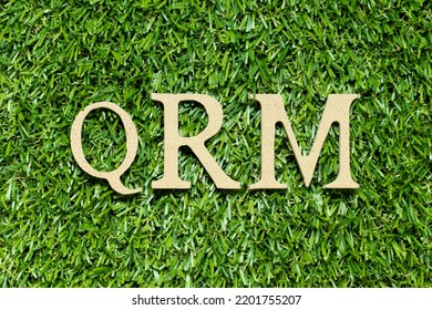 Wood Alphabet Letter In Word QRM (Abbreviation Of Quality Risk Management) On Green Grass Background