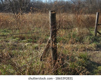 Wood and barb wire fence in a field - Shutterstock ID 1865392831