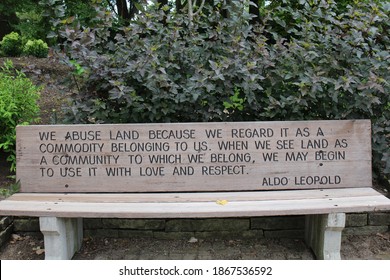 A wood bench engraved with an inspirational quote from Aldo Leopold in a park in Janesville, Wisconsin, USA