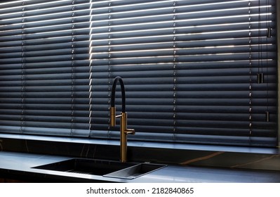 Wood Blinds Black Color Closeup On The Window. Wooden Slats 50mm Wide. Venetian Bamboo Blinds In The Kitchen. Black Tapes. Sink With Copper Faucet Near The Window. Stone Countertop.