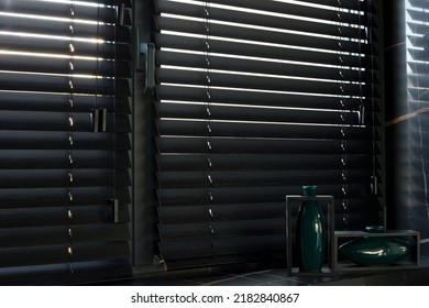 Wood blinds black color closeup on the window. Wooden slats 50mm wide. Venetian bamboo blinds in the kitchen. Black tapes. Green vases on the windowsill. Stone countertop.