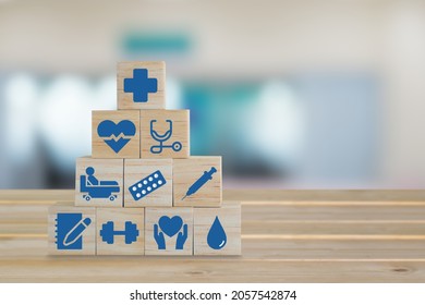 Wood Block With Healthcare Medical Icon On Blurred Background Of Emergency Room In Hospital. A Symbol That Represents Comprehensive Patient Care.