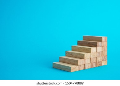 Wood block stack as stair step on blue background with copy space. Abstract business goal, target, growth or success plan concept.