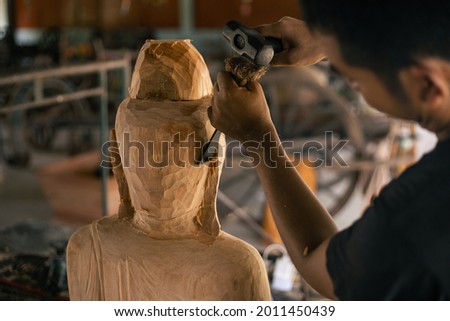 Wood buddha statue carved handmade. Asia craftsman professional carving with chisel in workshop. Carpentry woodwork. Handcraft carved. Selective focus.