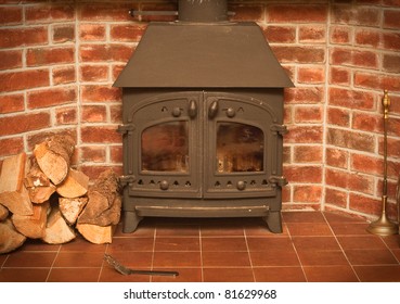 A wood burning stove in a red brick fireplace