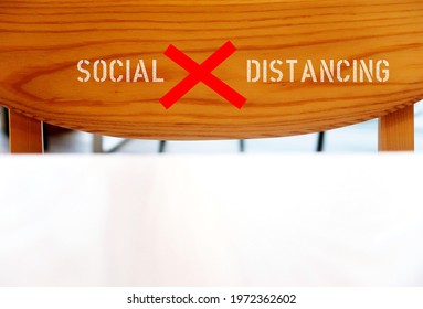 A Wood Chair Back With Blurred Table Foreground, With Text Inscription SOCIAL DISTANCING, Concept Of Safe Dining Restaurant By Limit Searing Capacity To Allow Distance To Customers