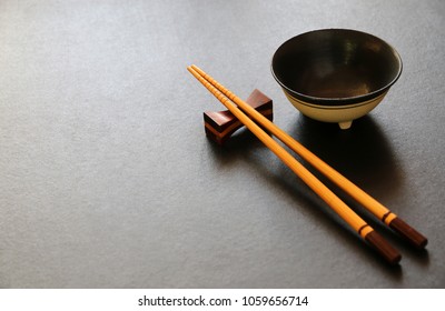 wood chopsticks and ceramic bowl on black table background - Powered by Shutterstock