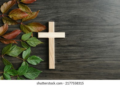 Wood Christian Cross With Border Of Green And Red Leaves On A Dark Wood Background With Copy Space