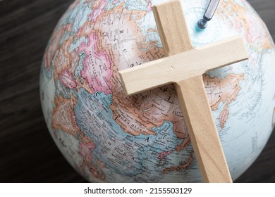 Wood Christian cross laying on a globe of the world