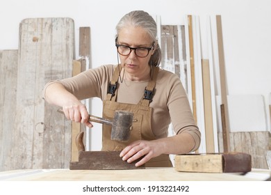 wood crafts, woman artisan carpenter works wood with old handle planer and hammer tools in her workshop, restoration, diy and handmade works concept - Powered by Shutterstock