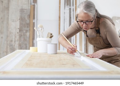 Wood Crafts, Woman Artisan Carpenter Painting With Brush And Paint Jar White The Door In Workshop, Wearing Overall And Eyeglasses, Interior Designer, Restoration, Diy And Handmade Works Concept