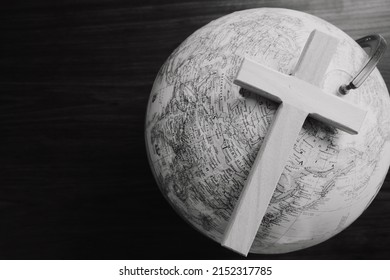 Wood cross on a globe against a dark wood background with copy space
