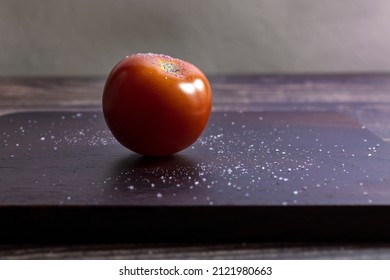 Wood cutting board with a salted tomato