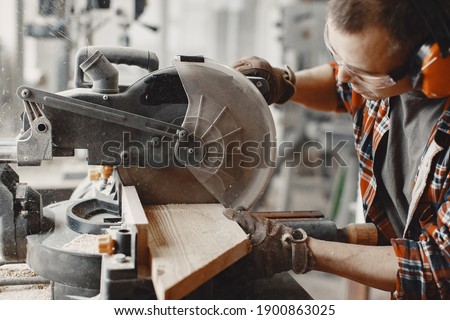 Wood cutting with circular saw. Closeup of mature man sawing lumber.