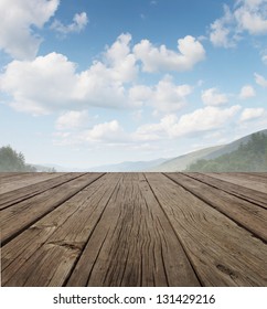 Wood Deck As A Tranquil Old Rustic Country Patio Floor In Perspective With A Summer Sky On A Beautiful Mountain Range With Forest Trees As A Symbol Of Travel And Backyard Living.