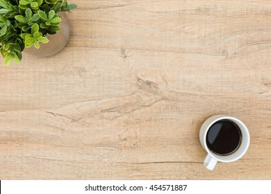 Wood Desk Table With A Cup Of Coffee And A Green Plant. Top View With Copy Space, Flat Lay. Minimal Concept.