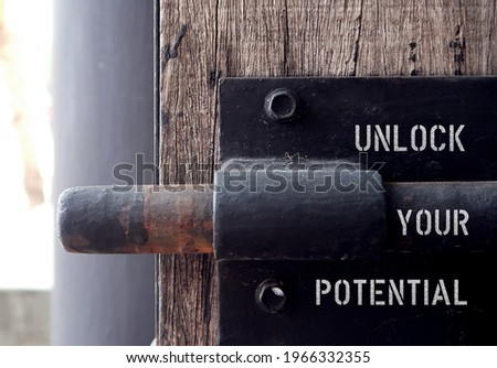 Wood door with steel old style lock, text inscription UNLOCK YOUR POTENTIAL ,concept of to unfold talents, when someone capable to do more, think less and act more, start to put dreams in practicality