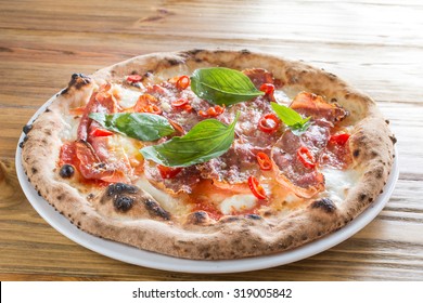 Wood fired oven Pizza with mozzarella, chili, speck and basil leaves