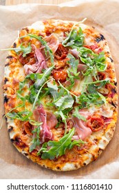 Wood fired pizza with tomato sauce, mozzarella, marinated cherry tomatoes, topped with rocket and parma ham. 