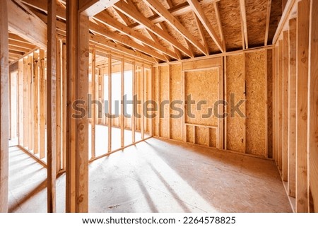 Wood framing and flooring structure with golden sunlight shining through window frame at empty room. New construction house, framework of real estate development industry. Renovation, building concept
