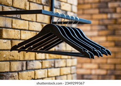 Wood Hangers coat. Many wooden black hangers on a rod. Store concept, sale, design, empty hangers. Wooden coat hanger clothes. Fashionable different types of hanger.