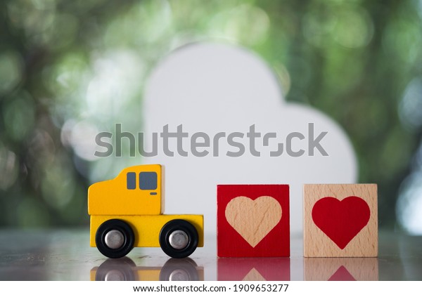 Wood heart follow yellow toy car\
for sending to couple. The concept of love and Valentine\'s\
day
