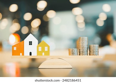 Wood house and Coins stack with balance scale. Money management, financial plan, time value of money. Real estate and property agent offer house concepts. - Powered by Shutterstock