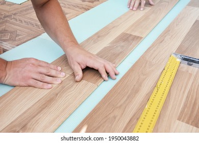 Wood laminate flooring installation: Laminate flooring installers are installing laminate hardwood planks over a soundproofing underlayment, insulation.  - Shutterstock ID 1950043882