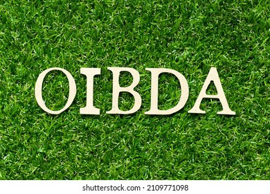 Wood letter in word OIBDA (Abbreviation of Operating Income Before Depreciation and Amortization) on green grass background