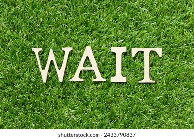 Wood letter in word wait on green grass background