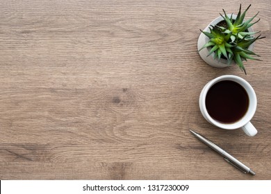 Schreibtisch aus Holz mit Tasse Kaffee, Stift und Kaktus-Topf. Draufsicht mit Kopienraum, flach, gelegt.