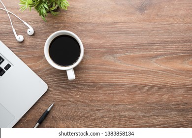 Wood Office Desk Table With Laptop Computer, Cup Of Coffee, Pen, Earphones And Plant Pot. Top View With Copy Space, Flat Lay.