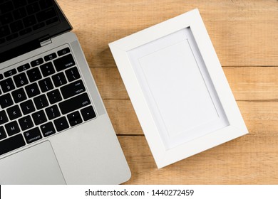 Wood Office Work Space Desk Table With Laptop And Blank Picture Frame, Small Plant, Pencil. Top View With Copy Space, Flat Lay.