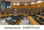 A wood paneled university lecture theatre or conference hall in business school timelapse. Laptop and remote control on the table