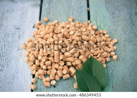 Wood pellets on a blue wooden background, two green leaf from a tree.Biofuels. Cat litter.