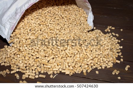 Wood pellets spill out of the packaging on wooden background . Biofuels. The cat litter.